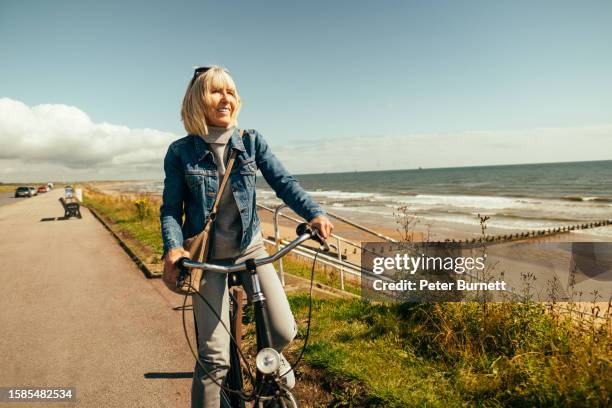 cycling along the beach esplanade at aberdeen,  scotland - active seniors biking stock pictures, royalty-free photos & images