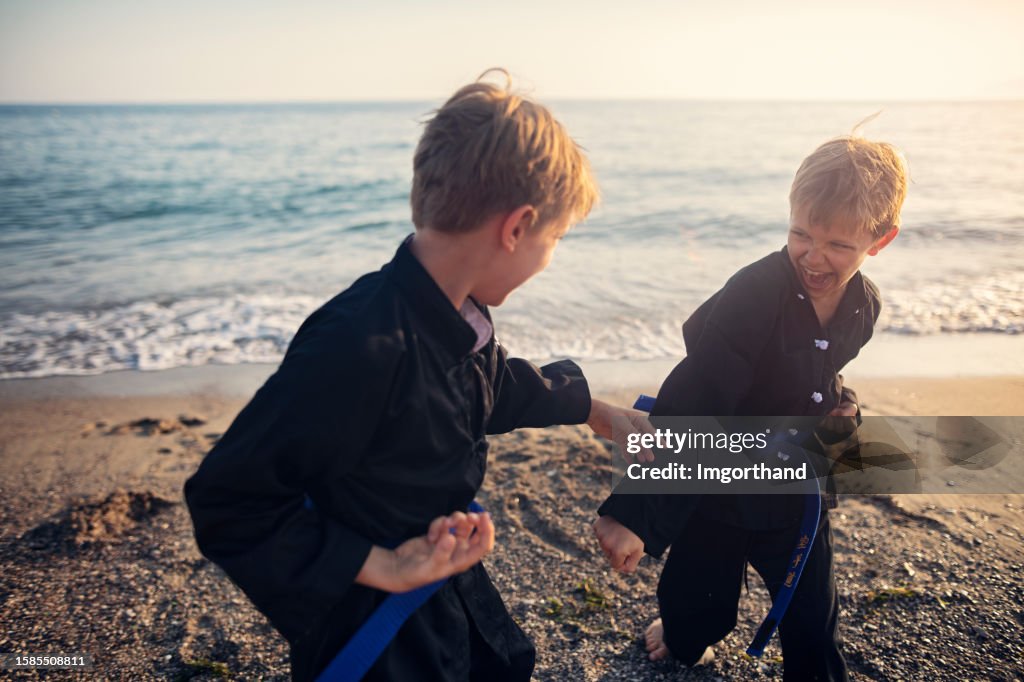 Kleine Kung Fu Jungen üben Kampfkünste am Strand