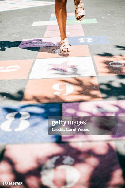 young girl jumps in a colorful hopscotch   with casting shadows - snakes and ladders stock pictures, royalty-free photos & images