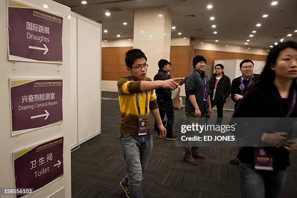 Staff member directs viewers to the venue of a 'blinfold' chess tournament at the Beijing 2012 World Mind Games Tournament in Beijing on December 19,...