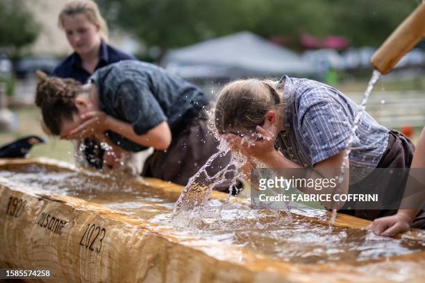Wrestlers wash their faces to remove sawdust at the fountain during the Women's wrestling festival of Romandy in Romanel-sur-Lausanne, on July 15,...