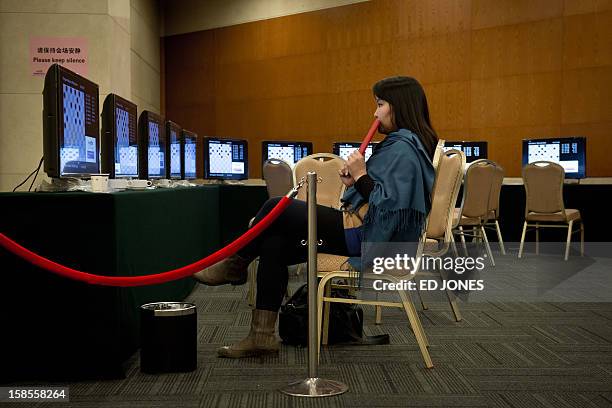 Woman watches a feed showing a 'blinfold' chess tournament at the Beijing 2012 World Mind Games Tournament in Beijing on December 19, 2012. Some of...