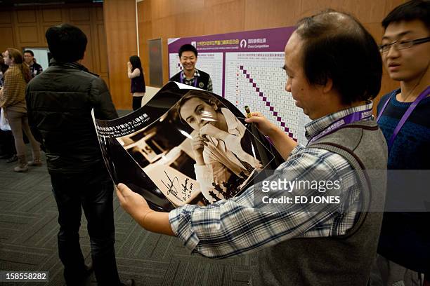 Chess fan holds a signed portrait of Antoaneta Stefanova of Bulgaria as she takes part in a 'blinfold' chess tournament at the Beijing 2012 World...
