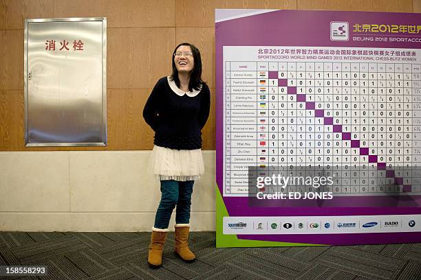 Chess player Hou Yifan of China stands beside a scoreboard following her win in a 'blinfold' chess tournament at the Beijing 2012 World Mind Games...