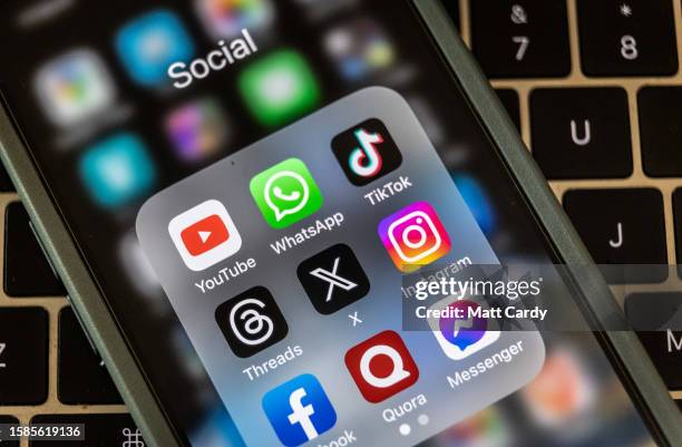 In this photo illustration the logo of US online social media and social networking site 'X' is displayed centrally on a smartphone screen alongside...