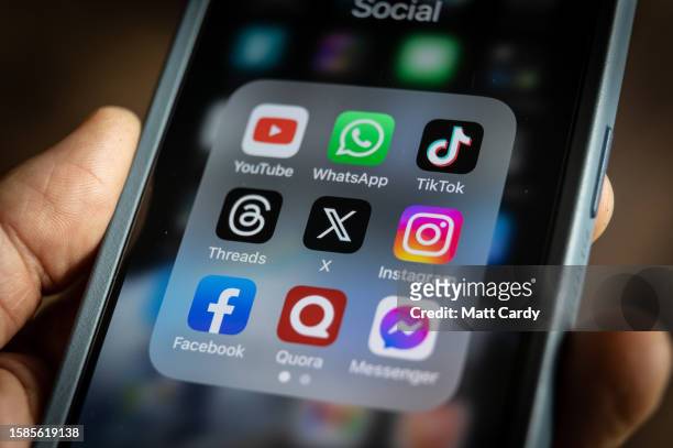 In this photo illustration the logo of US online social media and social networking site 'X' is displayed centrally on a smartphone screen alongside...