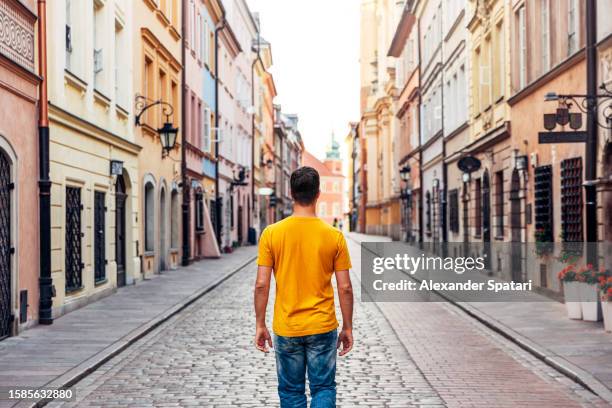 rear view of a man exploring streets of warsaw old town, poland - daily life in warsaw stock pictures, royalty-free photos & images