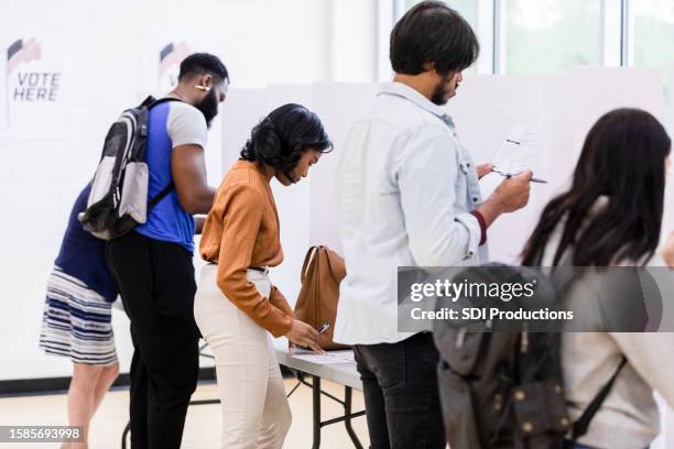 diverse group of voters stand quietly at voting booths - ballot paper stock pictures, royalty-free photos & images