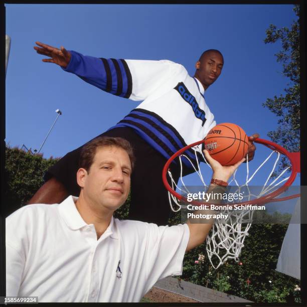 Athlete Kobe Bryant stands over agent Arn Tellem, who hands him a basketball, in Los Angeles in 1996.