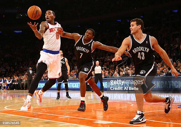 Smith of the New York Knicks grabs a rebound as Joe Johnson, and Gerald Wallace of the Brooklyn Nets defend during their game at Madison Square...