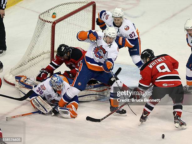 Joe Whitney of the Albany Devils is stopped by goaltender Kevin Poulin along with defensemen Nathan McIver and Aaron Ness of the Bridgeport Sound...