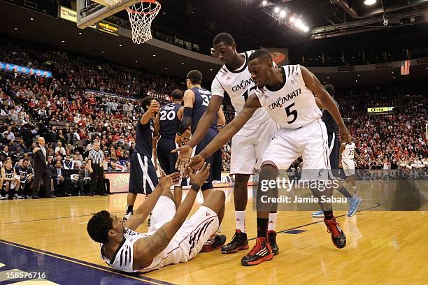 Cheikh Mbodj of the Cincinnati Bearcats and Justin Jackson of the Cincinnati Bearcats help teammate Jaquon Parker up after Parker commited a foul in...