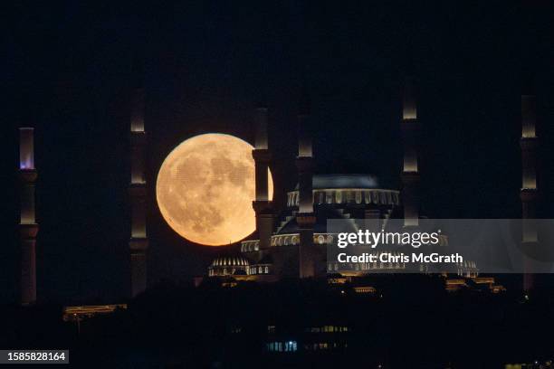 The Sturgeon full moon rises behind Istanbul's Camlica Mosque on August 01, 2023 in Istanbul, Turkey