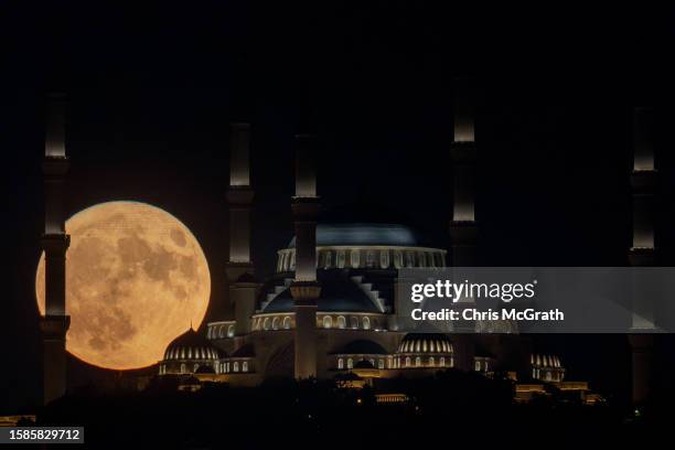 The Sturgeon full moon rises behind Istanbul's Camlica Mosque on August 01, 2023 in Istanbul, Turkey