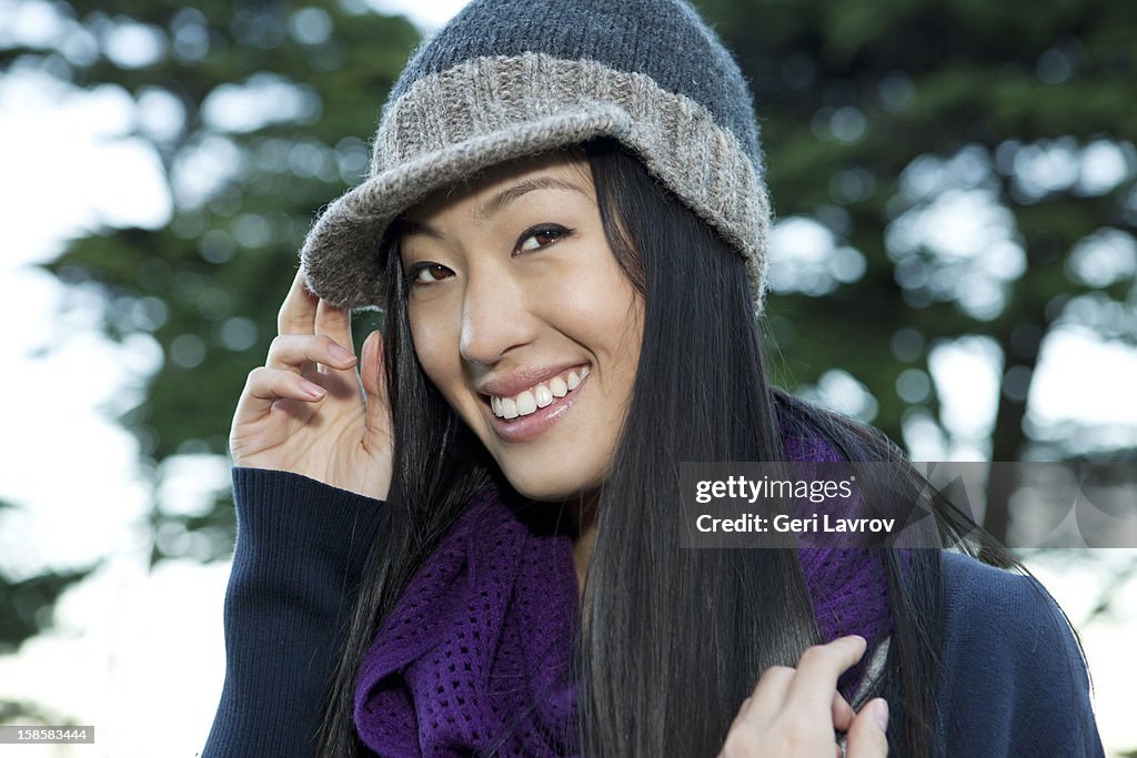 A smiling young Asian woman wearing a woollen hat