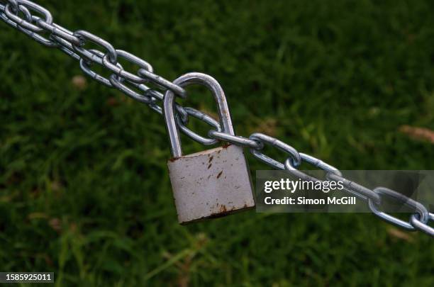 stainless steel chains held together by a rusting padlock - padlock stock pictures, royalty-free photos & images