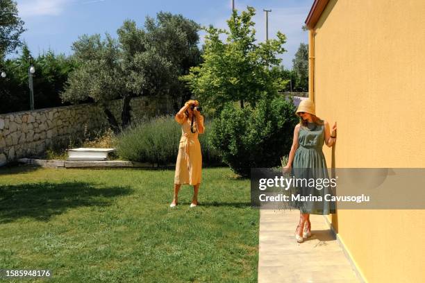 two woman in summer dresses and hats taking photos with a camera. - artists model stock photos et images de collection