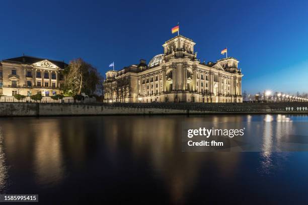 deutscher bundestag - reichstag building with spree river and german flag at blue hour (german parliament building) - berlin, germany - glaskuppel stock-fotos und bilder