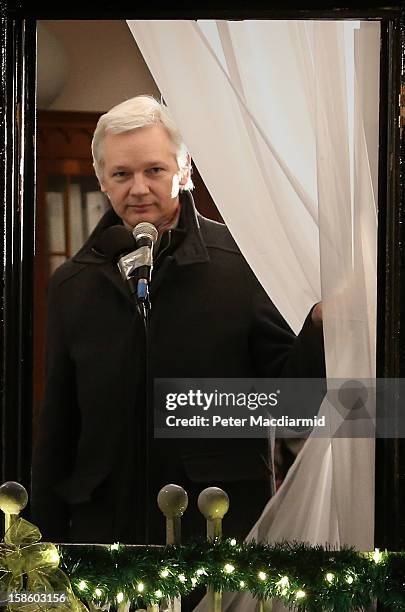 Wikileaks founder Julian Assange parts the curtains as he starts to speak from a balcony at the Ecuadorian Embassy on December 20, 2012 in London,...