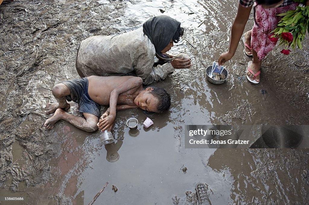 A woman and her son beg in the mud at the festival outside...
