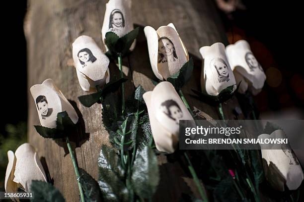 Pictures of victims of the Sandy Hook Elementary School shooting are seen on artificial roses at a roadside memorial December 20, 2012 in Newtown,...