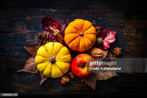 autumn decorative mini pumpkins with apple and fall leaves on dark wood background. thanksgiving or halloween holiday - old fashioned thanksgiving stockfoto's en -beelden