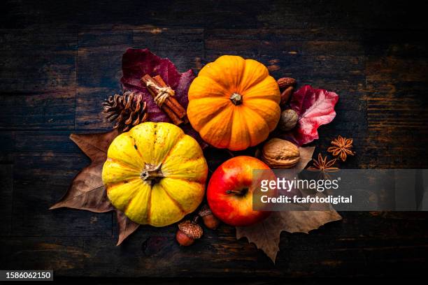 autumn decorative mini pumpkins with apple and fall leaves on dark wood background. thanksgiving or halloween holiday - thanksgiving arrangement stock pictures, royalty-free photos & images