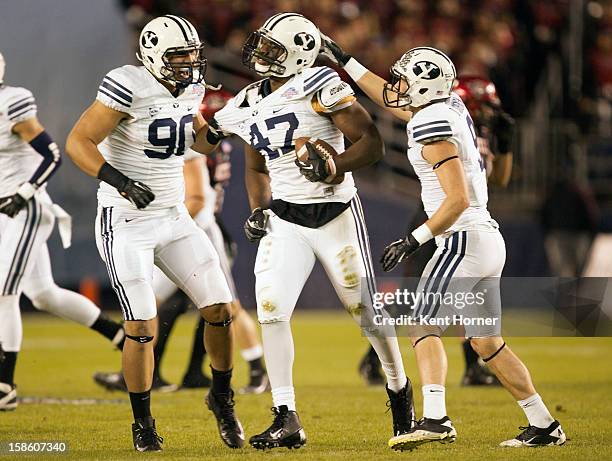 Ezekial Ansah of the BYU Cougars celebrates with teammates Branson Kaufusi and Daniel Sorensen after intercepting the ball in the first half of the...