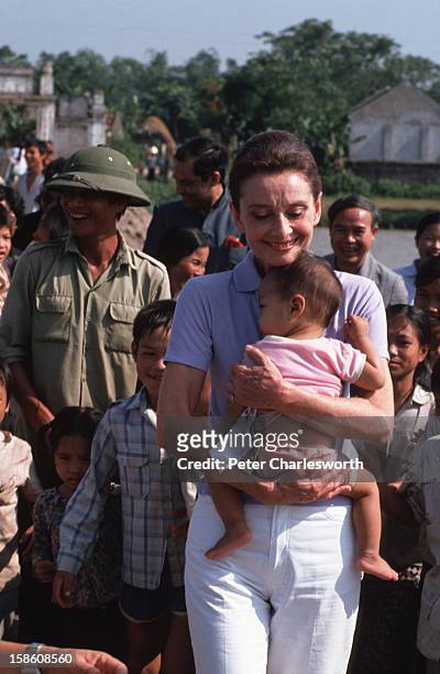 Audrey Hepburn, UNICEF's Goodwill Ambassador, clutches a small Vietnamese baby to her chest as she takes a walk about while visiting a small village...