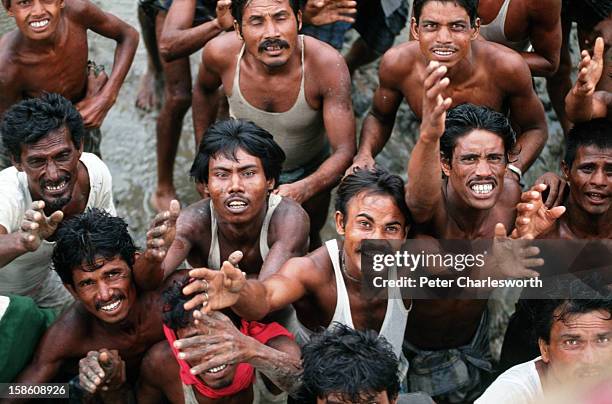 Villagers in a remote region of Bangladesh reach up for food being dropped from a helicopter bringing food and emergency supplies to those in need....