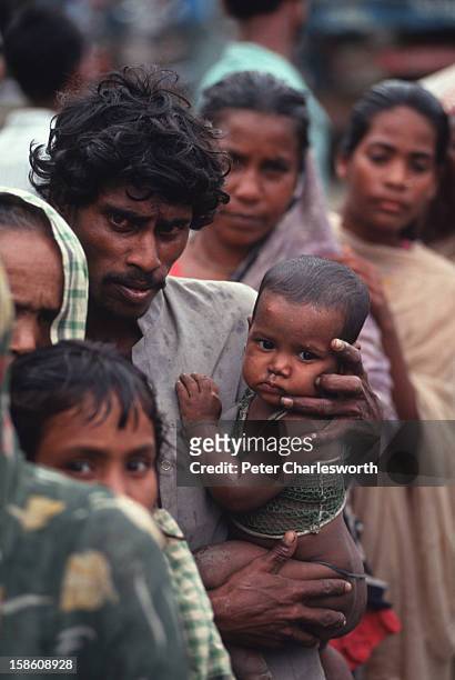 Father clutches his child as he and other villagers wait in in line for emergency relief that has finally arrived in Chittagong. Food and other...