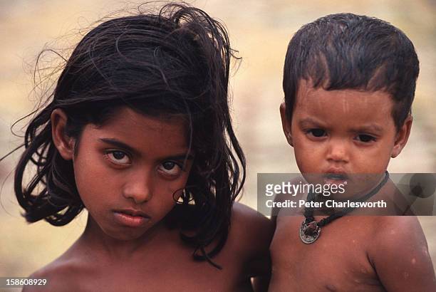 Young girl carries her brother looking dazed and confused after surviving one of the biggest cyclones to hit Bangladesh in recent decades. Thousands...
