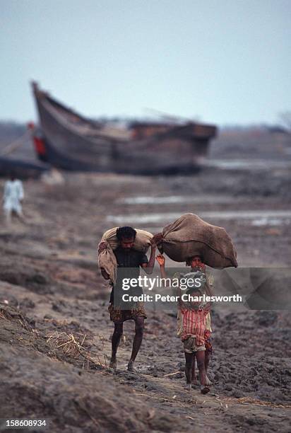 Man walks through muddy fields with his children with all their worldly possessions on their heads after surviving one of the biggest cyclones to hit...