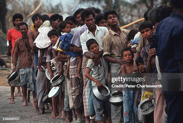Villagers wait in in line for emergency relief that has finally arrived in Chittagong. Food and other supplies were being dropped from helicopters to...