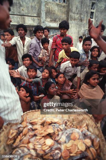 Villagers queue for emergency relief, packages of biscuits, that have arrived on an army helicopter. These young people have just survived one of the...