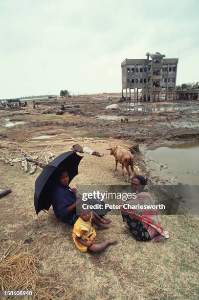 Villagers sit by the side of an all but destroyed dirt road with their storm-ravished farmlands a muddy wastland all around. They have just survived...