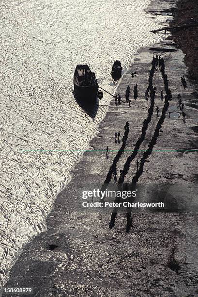 An aerial view of villagers queuing up for emergency relief brought by boat to their low-lying island off the mainland near Chittagong. They were...