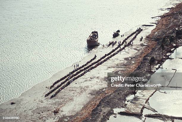 An aerial view of villagers queuing up for emergency relief brought by boat to their low-lying island off the mainland near Chittagong. They were...