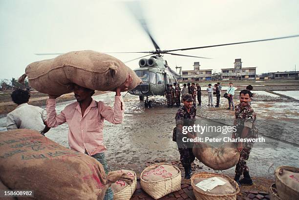 Sacks and baskets of food are unloaded from an army helicopter for distribution to island farmers who have just survived one of the biggest cyclones...