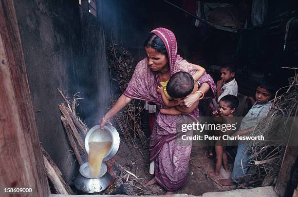 Bangladeshi family cooks lunch in the store room that they have made their home after their flimsy bamboo house was blown away by the recent cyclone....