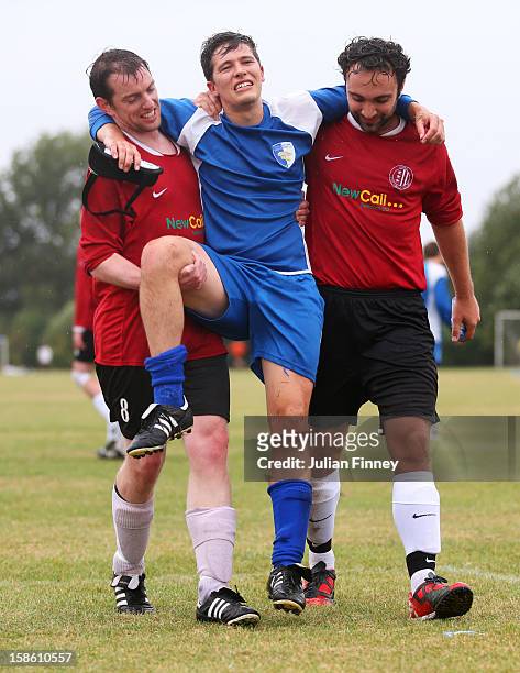Football player flanked by two others is carried off with an injury at Hackney Marshes on September 23, 2012 in London, England. Hackney Marshes in...
