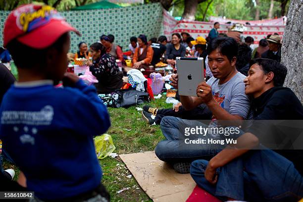 Tibetan use Apple Ipad to take photos during the Sho Dun Festival in Norbulingka on August 18, 2012 in Lhasa, China. Lhasa is the administrative...