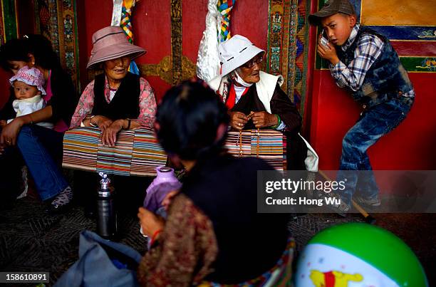 Tibetan child uses mobile phone with an elder Tibetan woman during the Sho Dun Festival in Norbulingka on August 18, 2012 in Lhasa, China. Lhasa is...