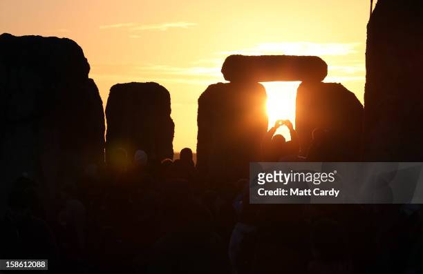 Man takes a photograph of the sunrise as druids, pagans and revellers celebrate the winter solstice at Stonehenge on December 21, 2012 in Wiltshire,...