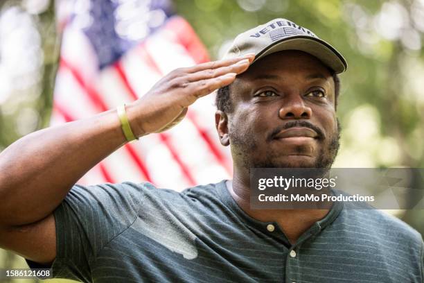 u.s. military veteran saluting in front of american flag - kriegsveteranen gedenktag stock-fotos und bilder