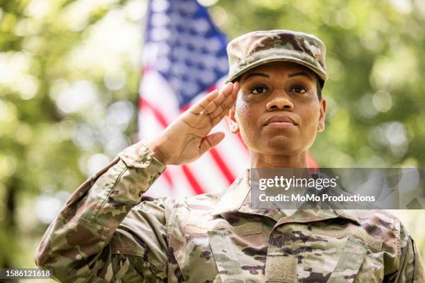 female u.s. soldier wearing 2023 ocp uniform saluting in front of american flag - uniforme militaire photos et images de collection