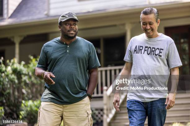 two senior military veterans walking and talking in front of suburban home - friendly neighbor stock pictures, royalty-free photos & images
