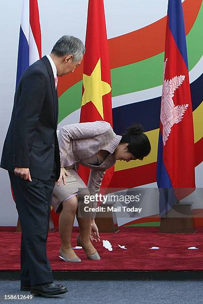 Thailand Prime Minister Yingluck Shinawatra manages to remove a paper glued to her shoes as she arrives for a photo opportunity with other leaders...