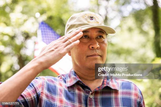 u.s. military veteran saluting in front of american flag - national guard stock pictures, royalty-free photos & images