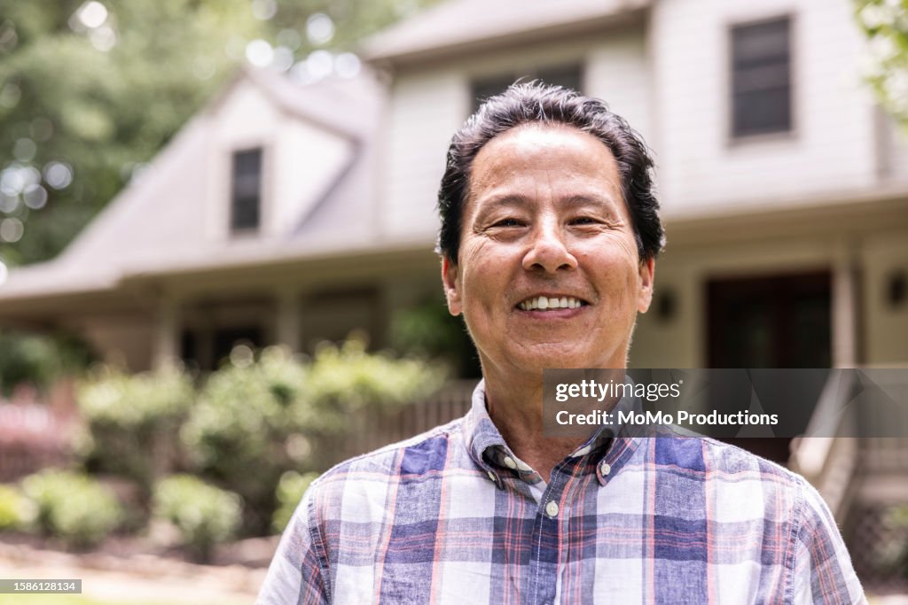 Portrait of proud senior man in front of suburban home